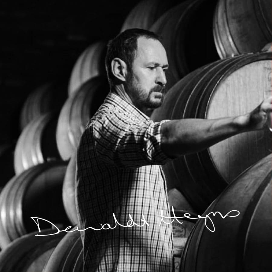Winemaker inspecting barrels in Stellenbosch winery.